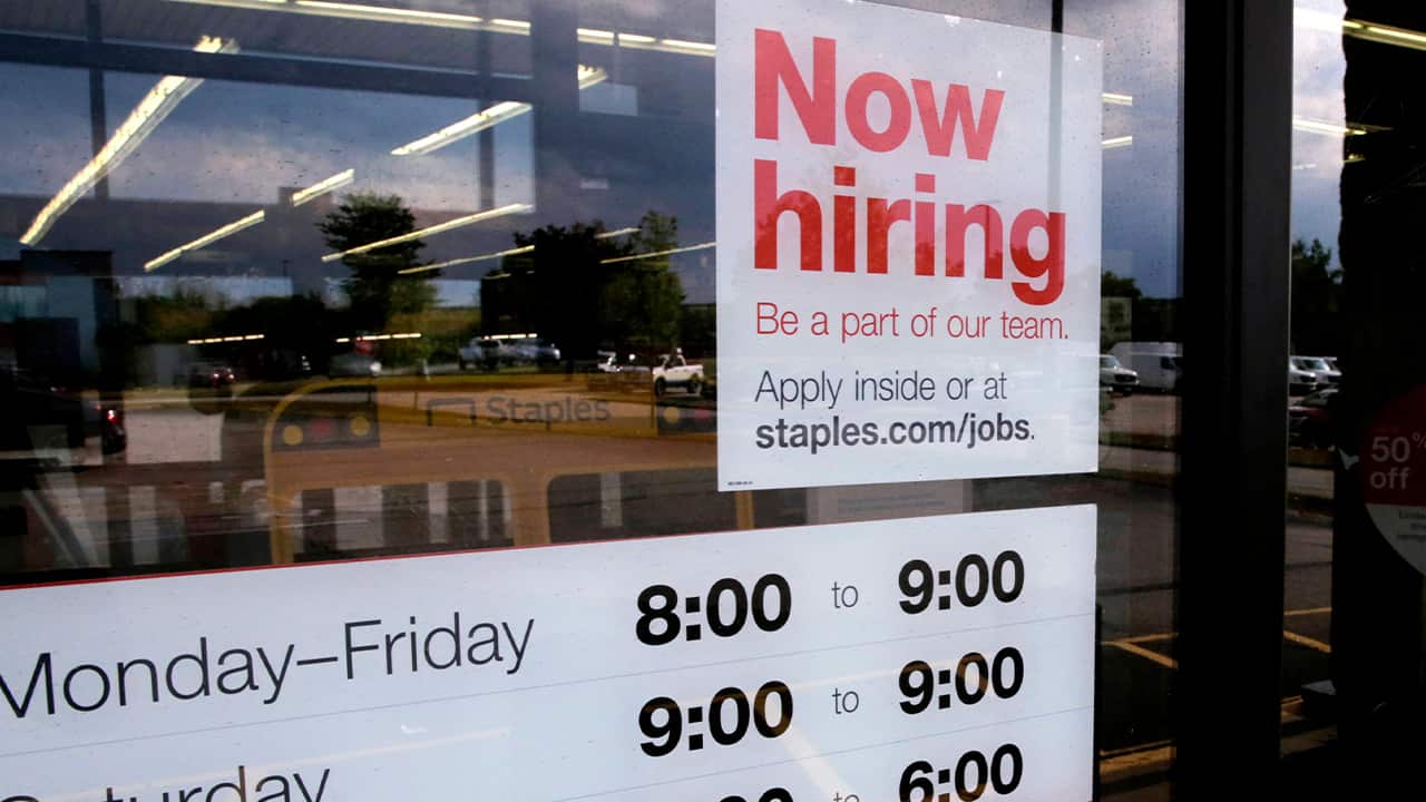 Photo of "Now Hiring" sign on the front door of a Staples store