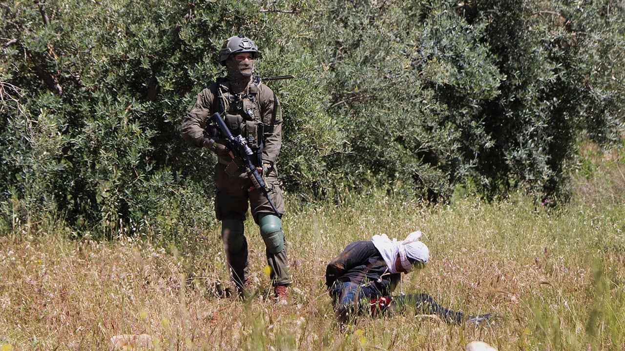 Photo of an Israeli soldier standing over handcuffed and blindfolded Osama Hajahjeh