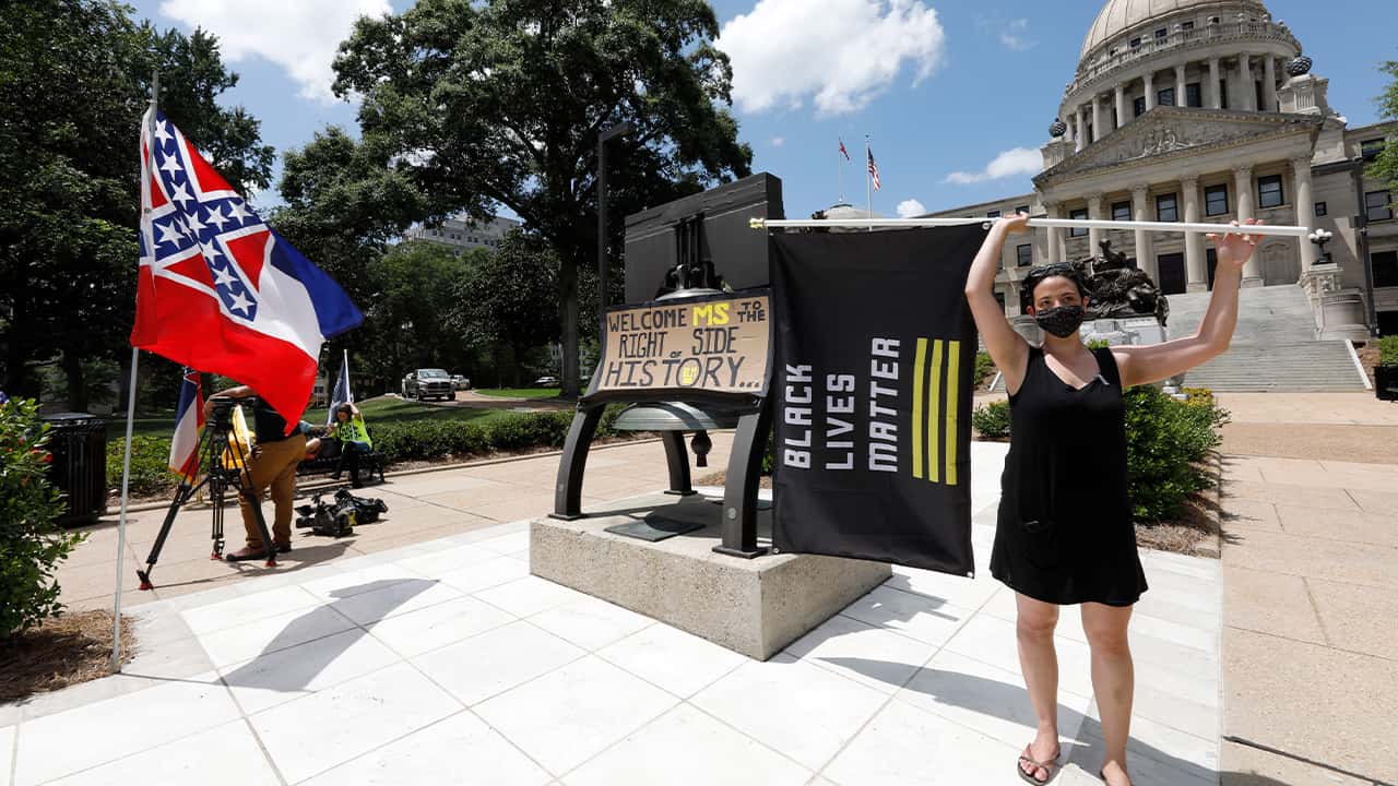 Photo of a woman holding a Black Lives Matter flag