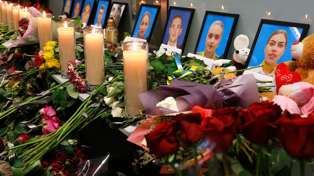 Photo of flowers and candles surrounding portraits of the flight crew members on the Ukrainian plan that crashed