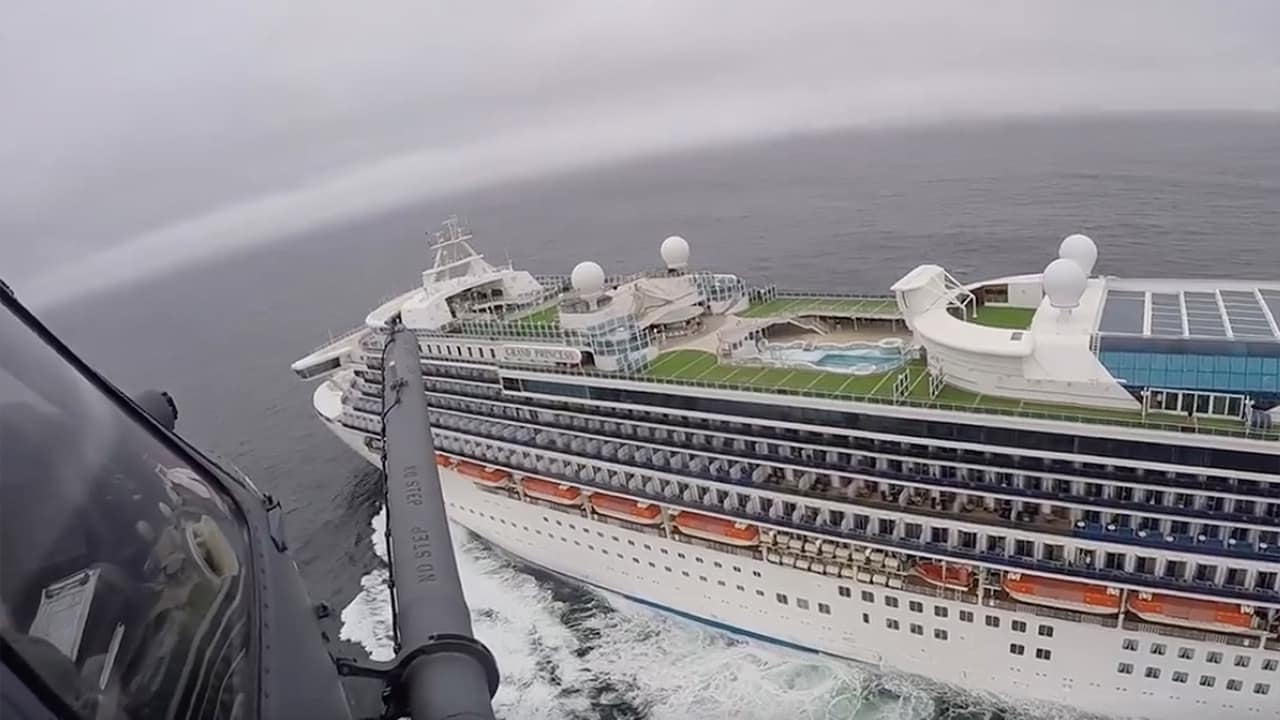 Photo of a helicopter carrying airmen with the 129th Rescue Wing flying over the Grand Princess cruise ship