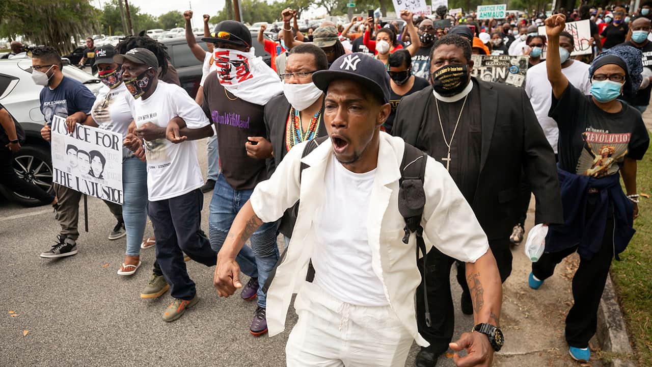 Photo of a group of people marching from the Glynn County Courthouse in downtown to a police station
