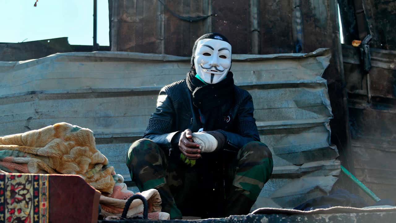 Photo of a protester wearing a Guy Fawkes mask