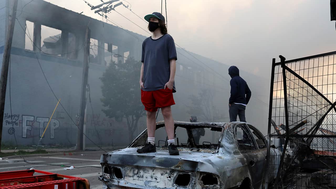 Photo of a man standing on a burnt car
