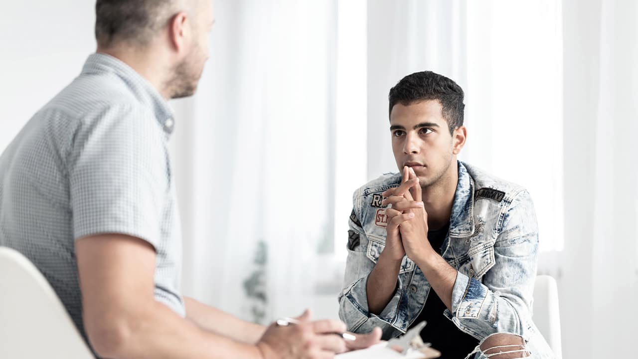 Photo of a psychologist counseling a male teenager