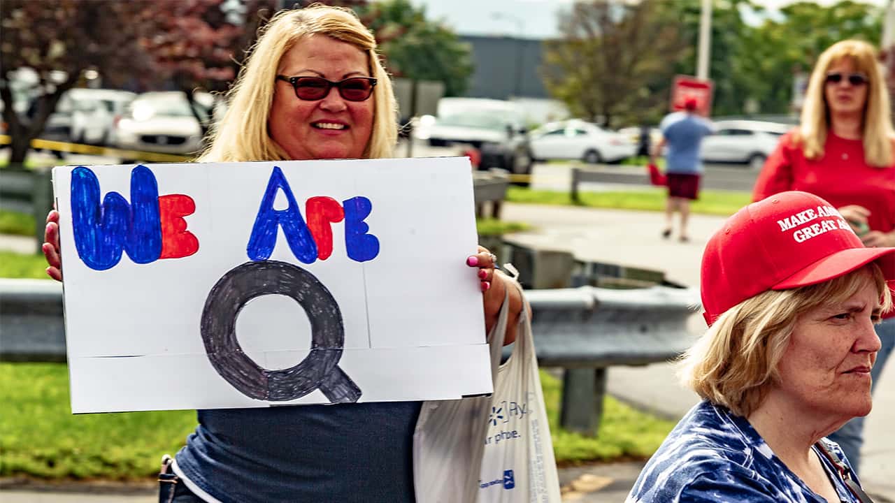 Picture of a woman with a "We are Q" sign at at a 2018 Make America Great Again rally in Wilkes-Barre, Pennsylvania