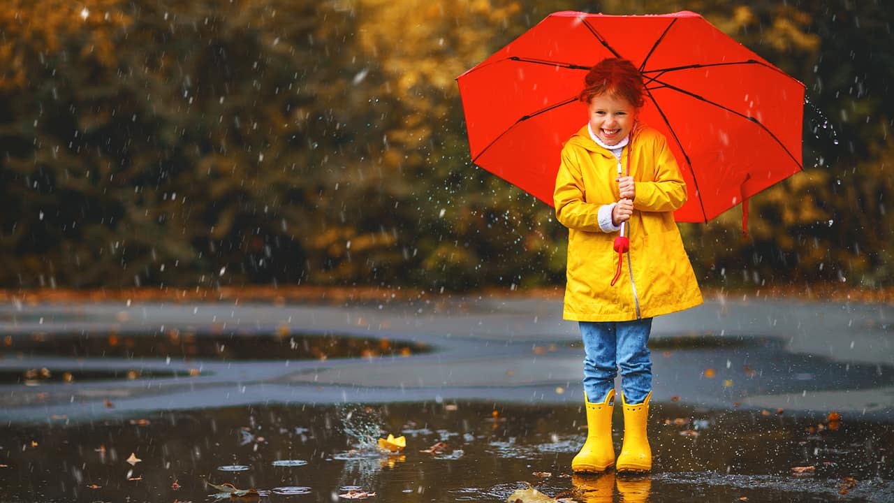 Picture of a young girl in yellow rain boots with a red umbrella