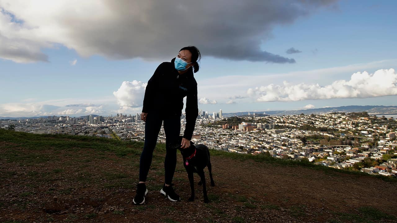 Photo of a woman wearing a mask while walking her dog 