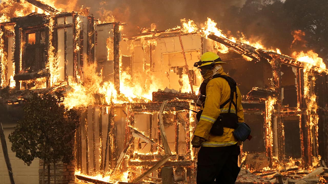 Photo of a firefighter monitoring a house burning in Santa Rosa, Calif.
