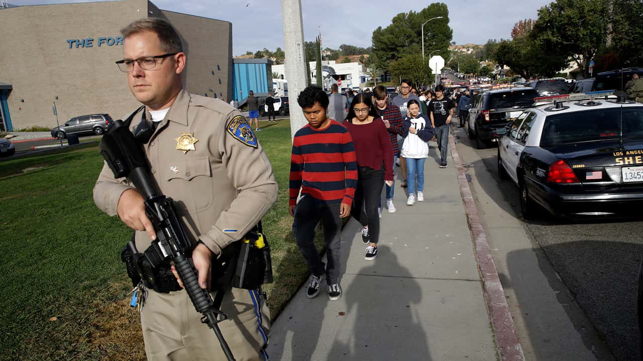 Photo of a CHP officer escorting students out of Saugus High School