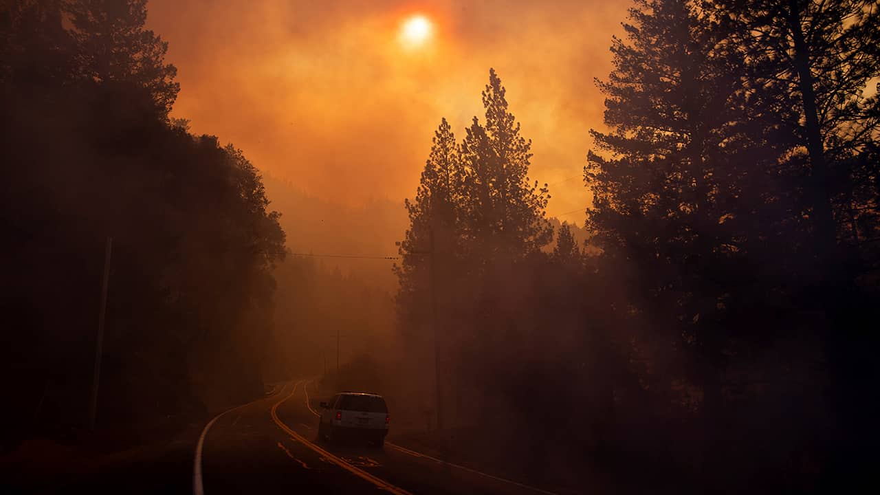 Photo of a car driving through smoke from a wildfire in Pulga, CA