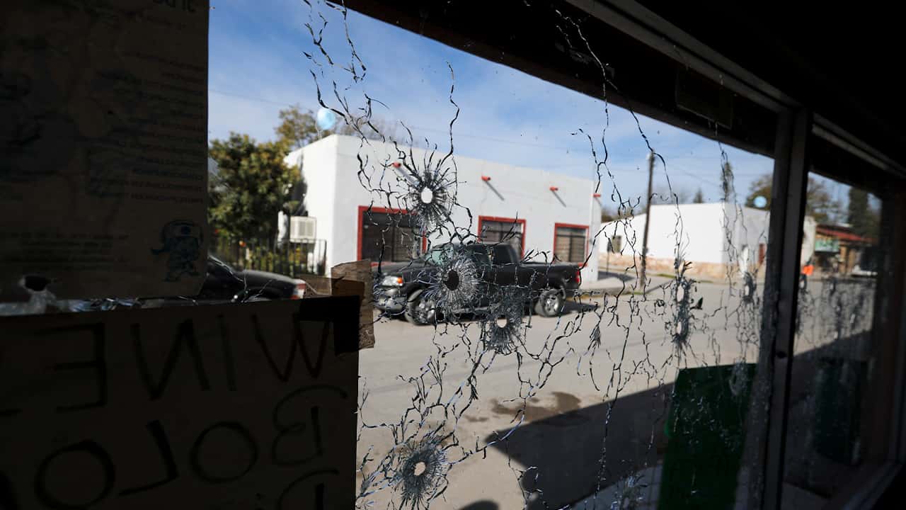 Photo of a shop window riddled with bullet holes
