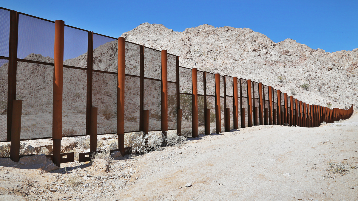 Photo of steel fence protecting the border between Mexico and the United States at the Tinajas Altas Mountains in Arizona.