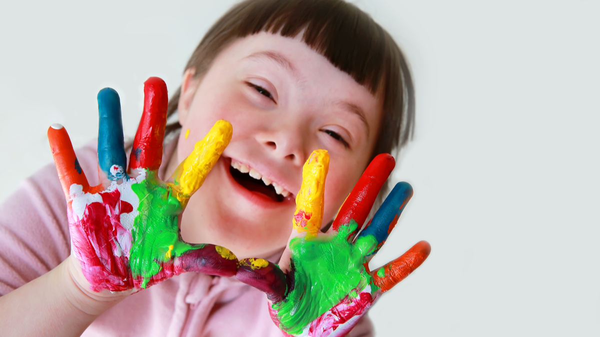 Photo of young girl with down syndrome showing off her painted hands