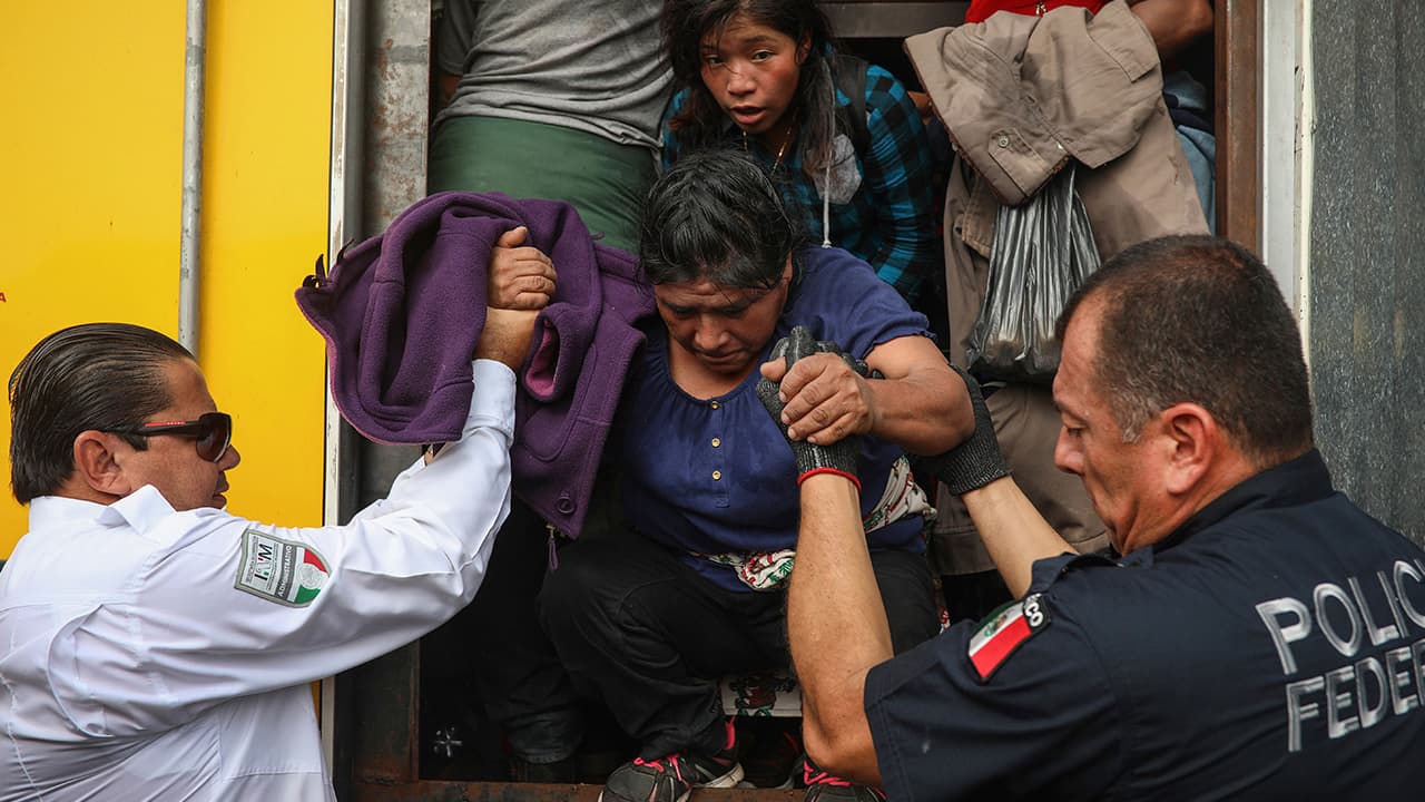 Photo of a police officer helping a woman off the cargo hold of a truck 