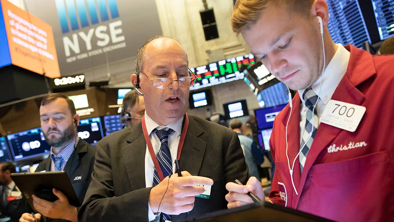 Photo of Gordon Charlop, center, and Christian Bader working at the New York Stock Exchange