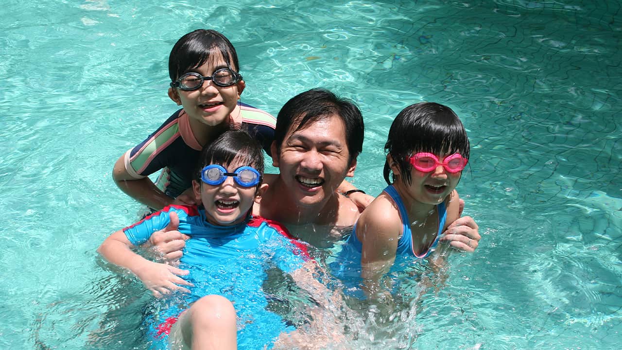 Photo of a dad with his children in a swimming pool on Father's Day