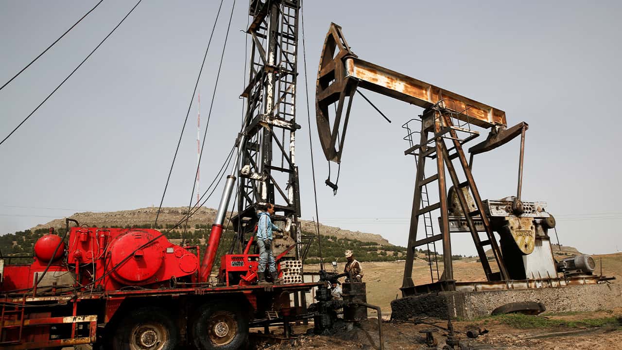 Photo of Syrian workers fixing pipes of an oil well 