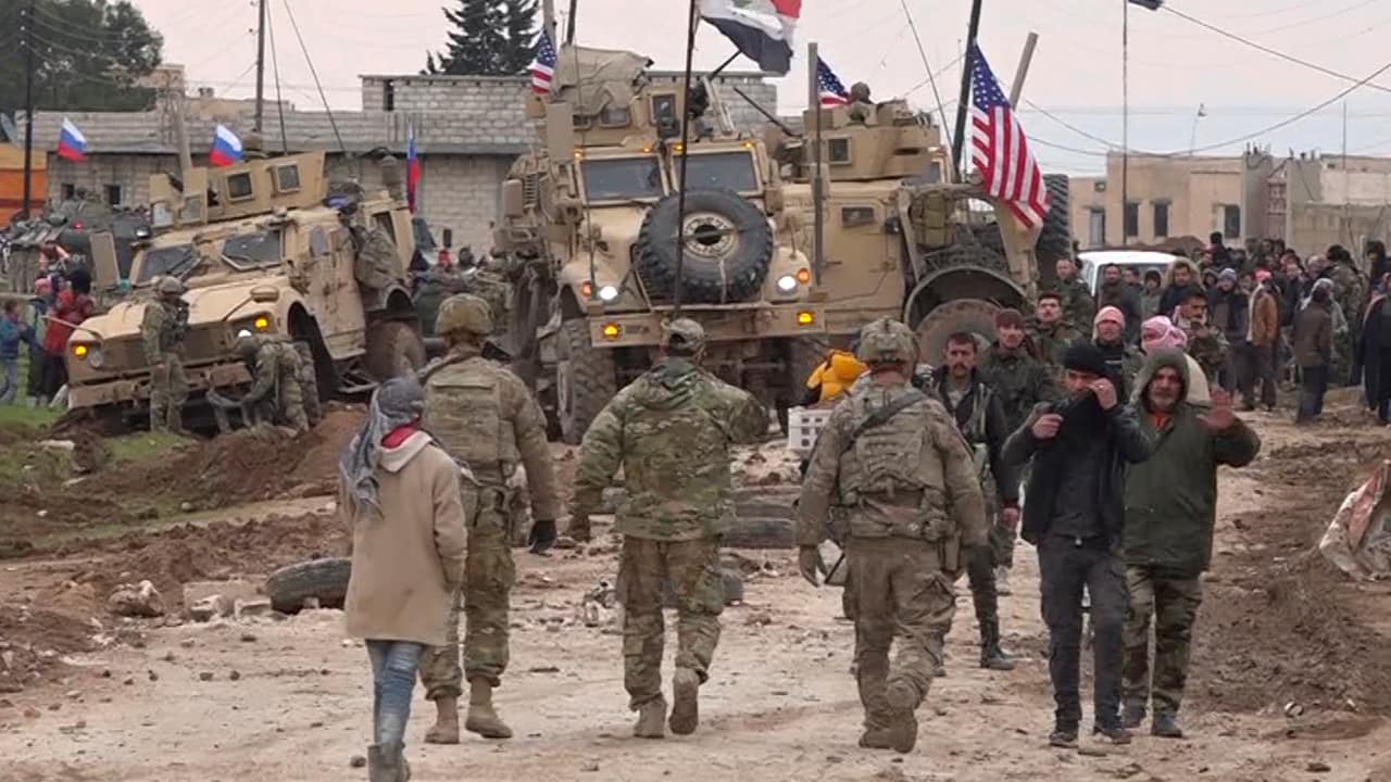 Photo of Russian, Syrian and others gather next to an American military convoy