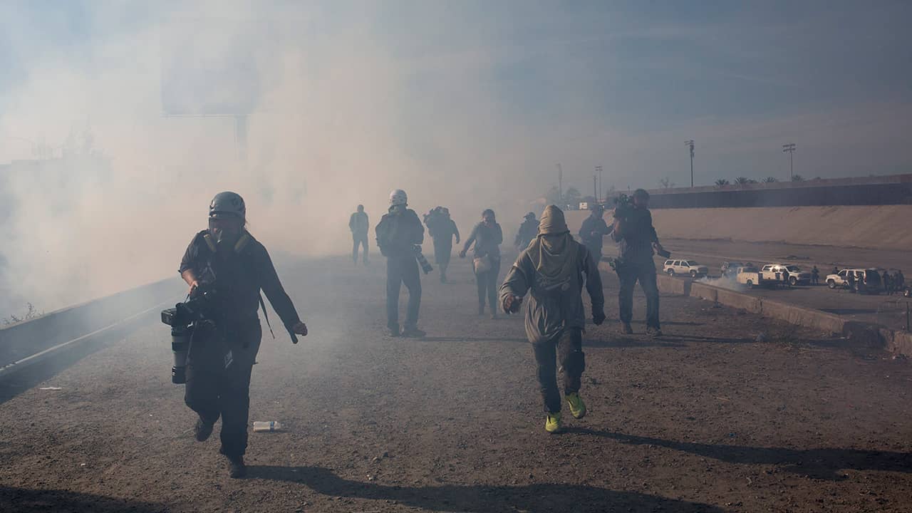 Photo of migrants running from tear gas