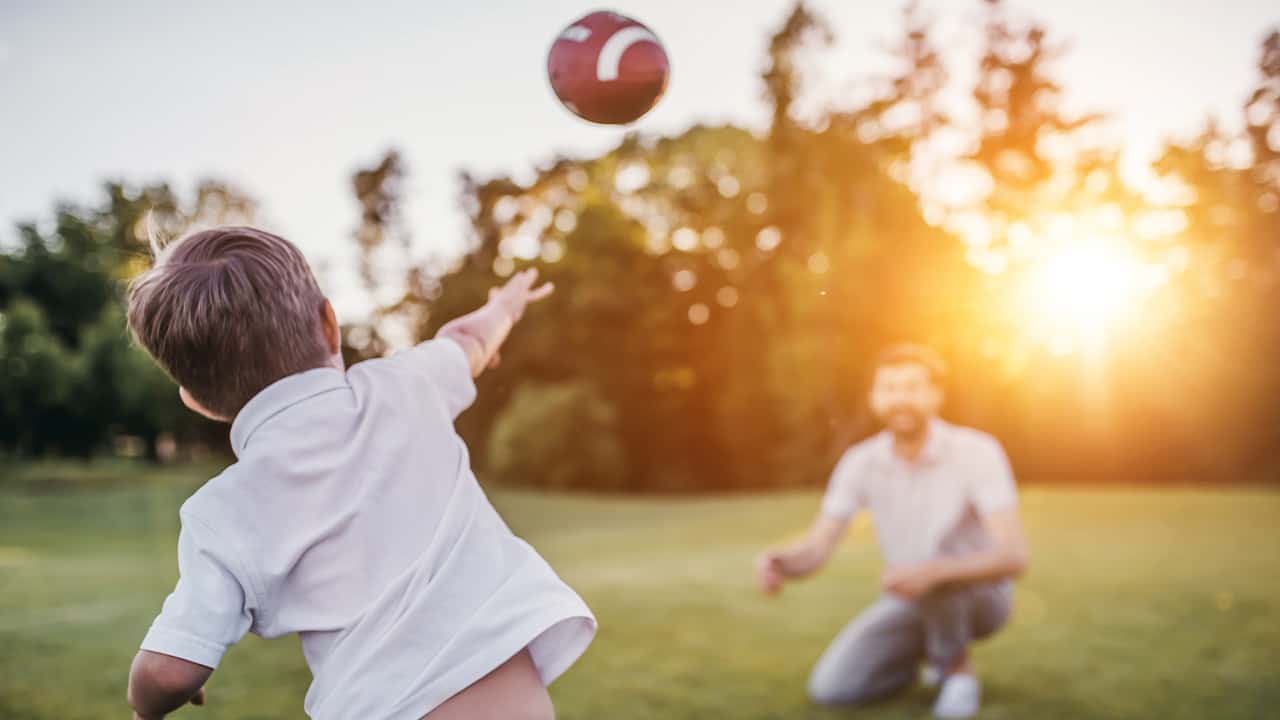 Photo of a son throwing a football to his dad