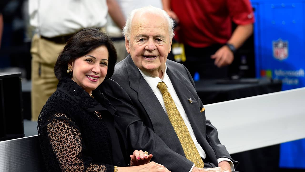 Photo of New Orleans Saints owner Tom Benson sits on the sideline with his wife, Gayle Benson 