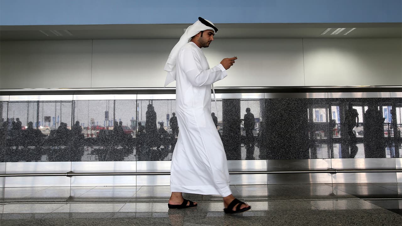 Photo of a worker looking at his phone at the airport in Dubai