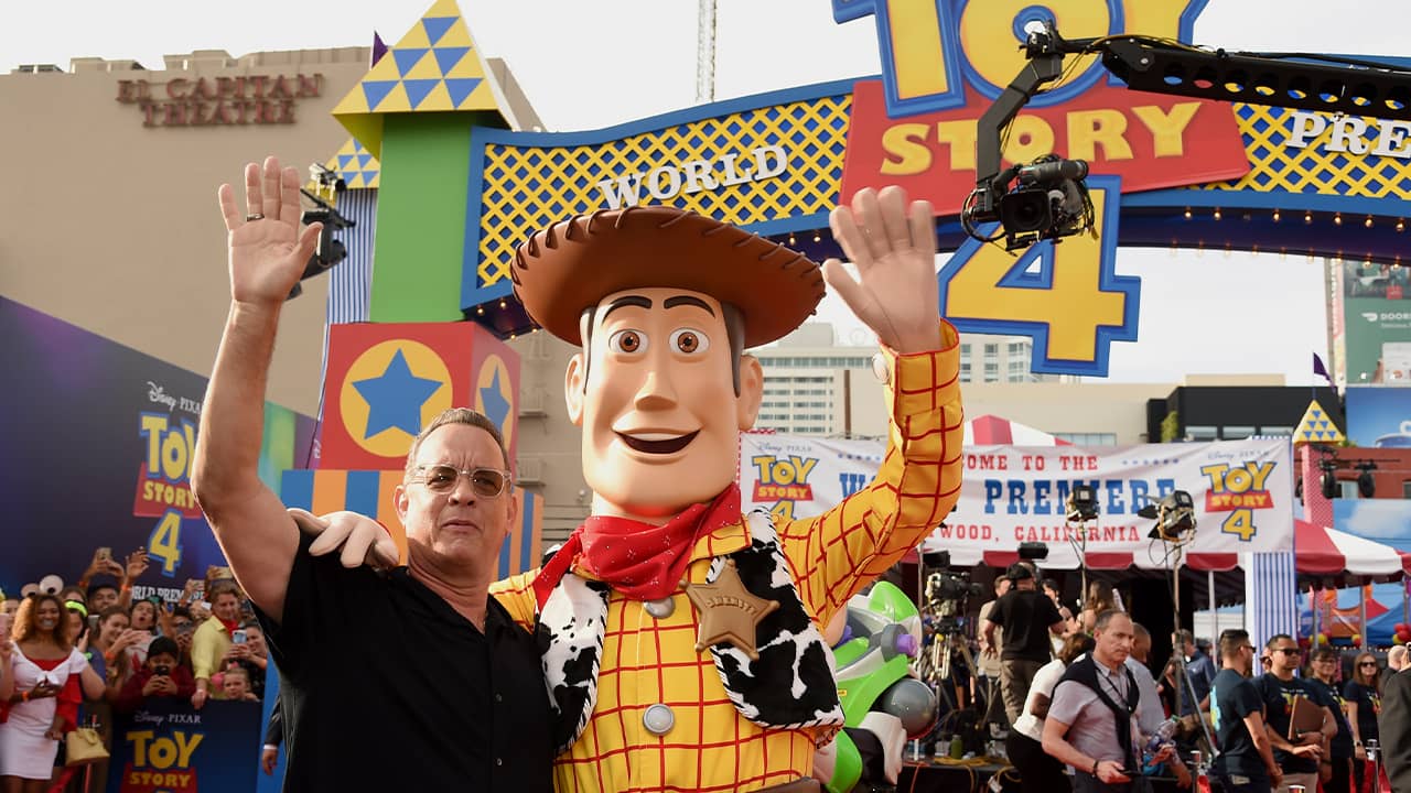 Photo of Tom Hanks posing with his character, Woody