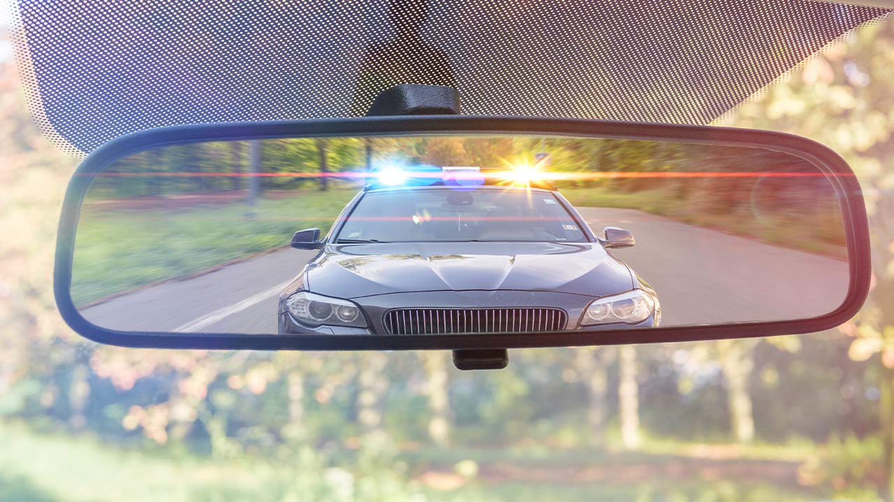 Photo of a cop car seen through a rear-view mirror