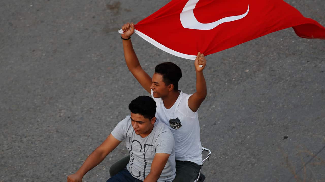 Photo of to men on a motorcycle holding the Turkish flag in the air