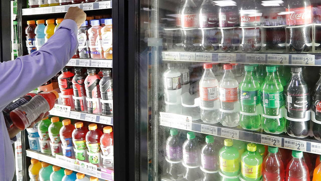 Photo of a shop owner reaching into a refrigerator