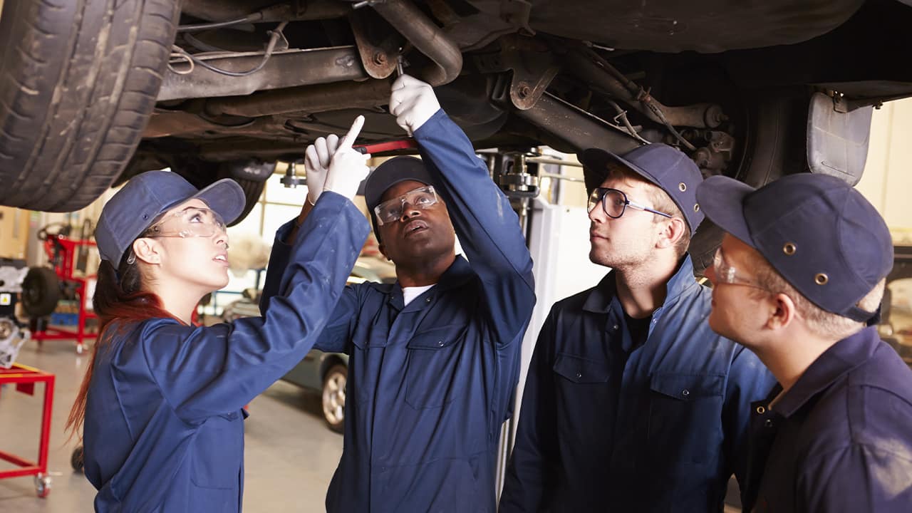 Photo of people in a shop class looking at a car