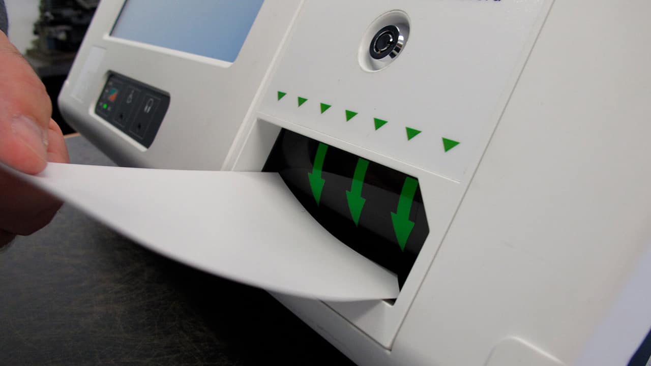 Photo of a man feeding a ballot card into a voting machine