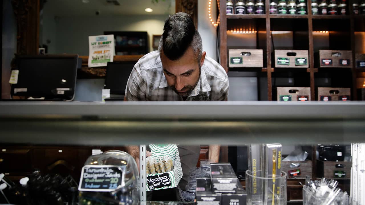 Photo of Jerred Kiloh stocking shelves with cannabis products