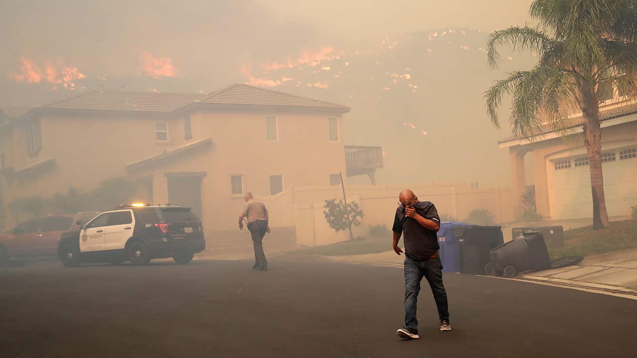 Photo of a resident covering his face as he is evacuated 