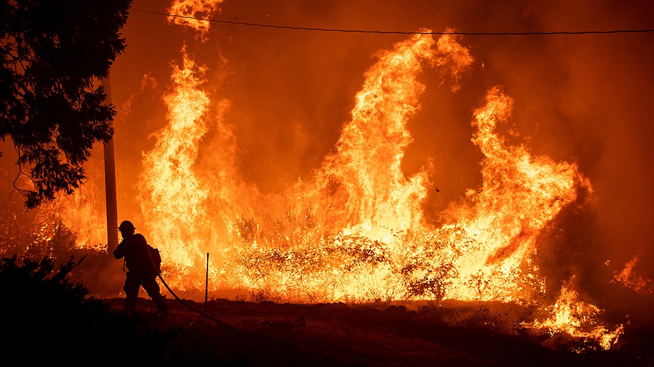 Photo of a firefighter passing through flames while battling Delta Fire