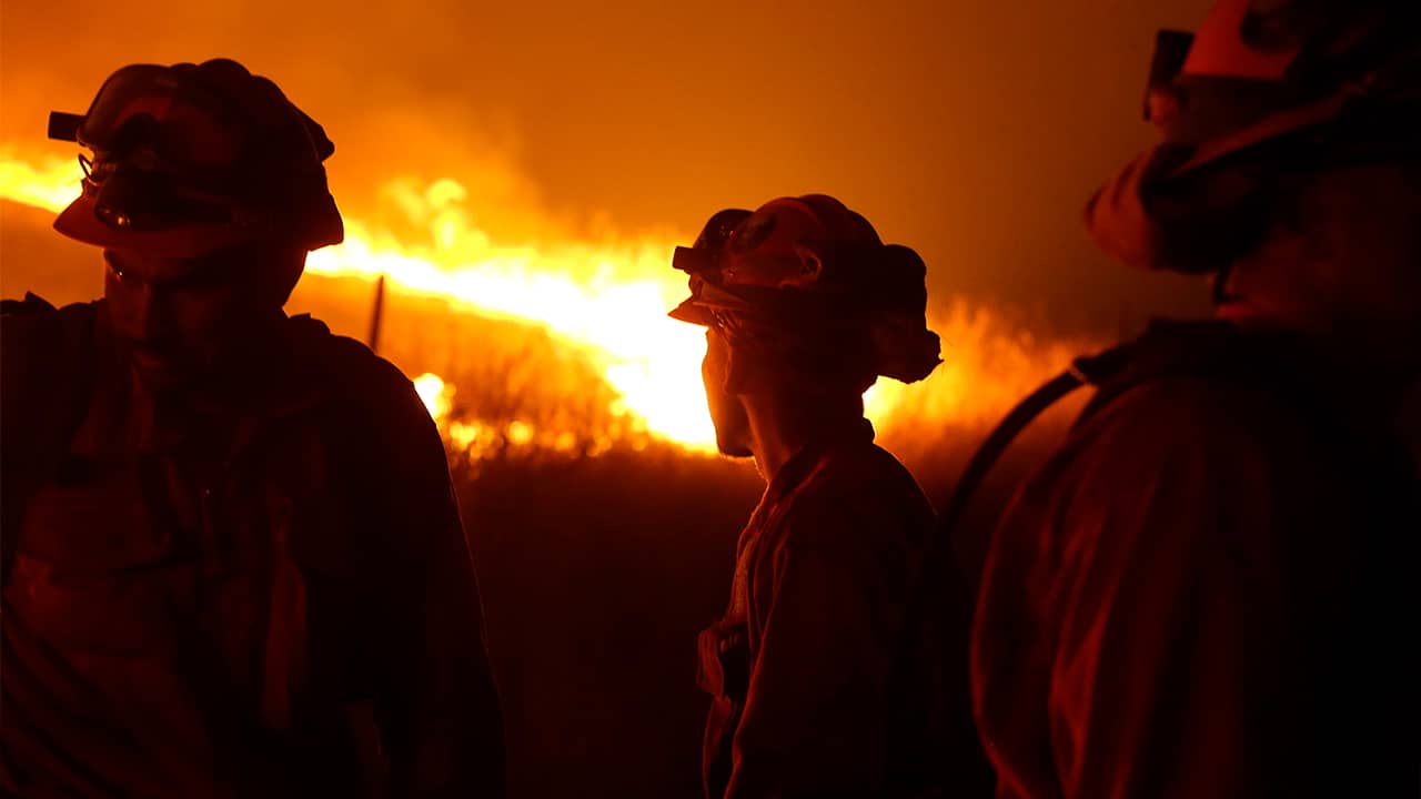 Photo of CDCR inmates standing guard as flames from the Butte fire approach a containment line