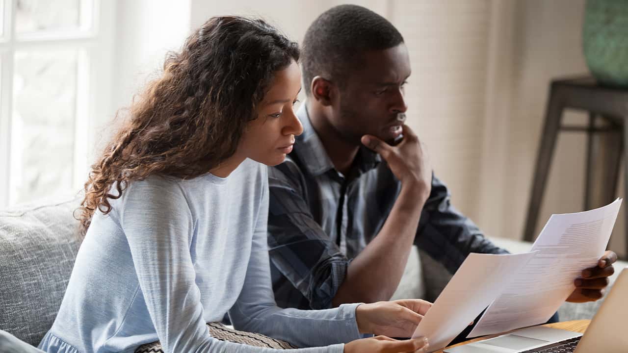 Image of a young African American couple poring over their monthly expenses
