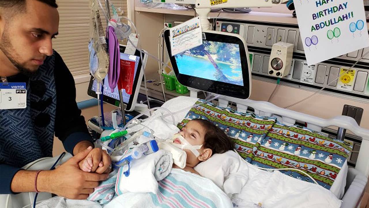 Photo of Ali Hassan with his dying 2-year-old son Abdullah