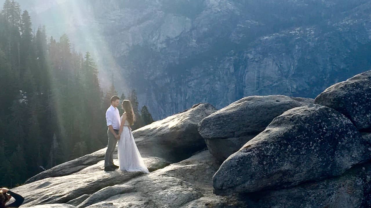 Photo of a couple at Yosemite's Glacier Point bathed in a ray of sunlight