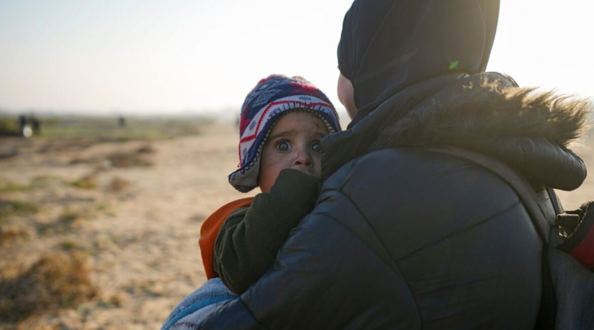A Palestinian woman holds a baby as they return to their home in the northern Gaza Strip, following Israel's decision to allow thousands of them to go back for the first time since the early weeks of the 15-month war with Hamas, Monday, Jan. 27, 2025. (AP Photo/Abdel Kareem Hana)