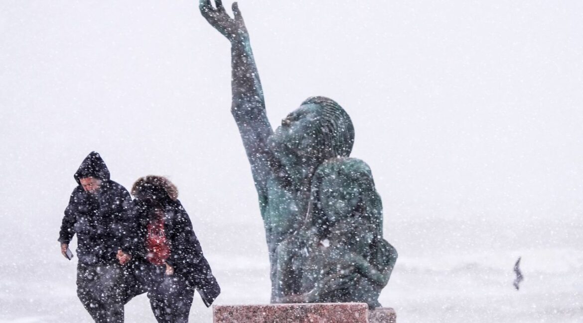 People walk past the 1900 Storm memorial sculpture on Seawall Blvd. during an icy winter storm on Tuesday, Jan. 21, 2025 in Galveston, Texas. (Brett Coomer/Houston Chronicle via AP)