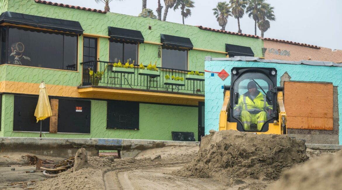 A public works employee builds sand berms to protect homes along the beach from expected storm surge in Capitola, Calif., Feb. 13, 2025. A large swath of California was bracing on Thursday for an intense bout of rain that could lead to flooding and cause debris flows in areas recently burned by wildfires. (Nic Coury/The New York Times)