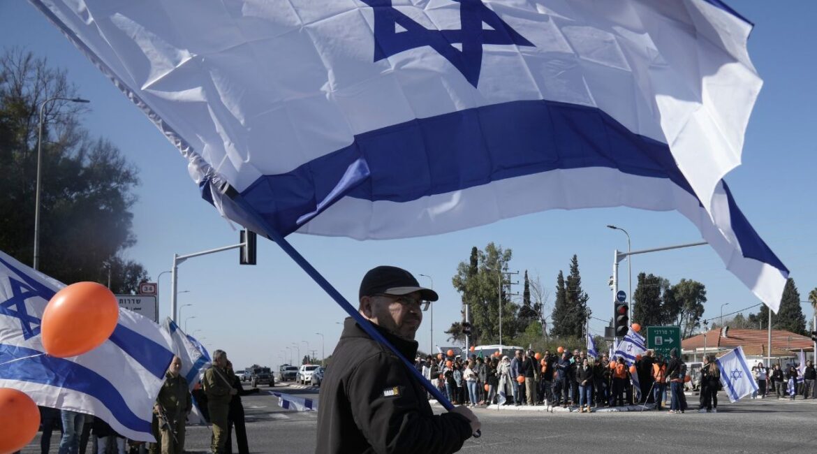 Israelis gather on the side of a road where the funeral convoy carrying the coffins of slain hostages Shiri Bibas and her two children, Ariel and Kfir, will pass by near Kibbutz Yad Mordechai, Israel, Wednesday, Feb. 26, 2025. The mother and her two children were abducted by Hamas on Oct. 7, 2023, and their remains were returned from Gaza to Israel last week as part of a ceasefire agreement with Hamas. (AP/Maya Alleruzzo)