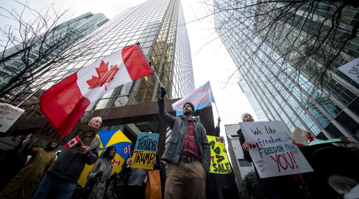 People wave flags and hold signs during a protest outside of the U.S embassy in Vancouver, British Columbia, Tuesday, March 4, 2025. (Ethan Cairns/The Canadian Press via AP)