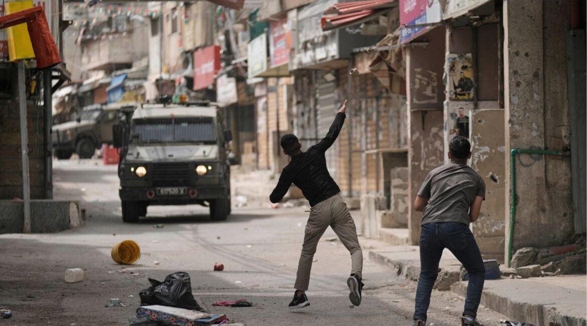 Palestinians hurls a stone at Israeli forces following a military raid in the West Bank refugee camp of Balata, on Wednesday, April 9, 2025. (AP/Majdi Mohammed)