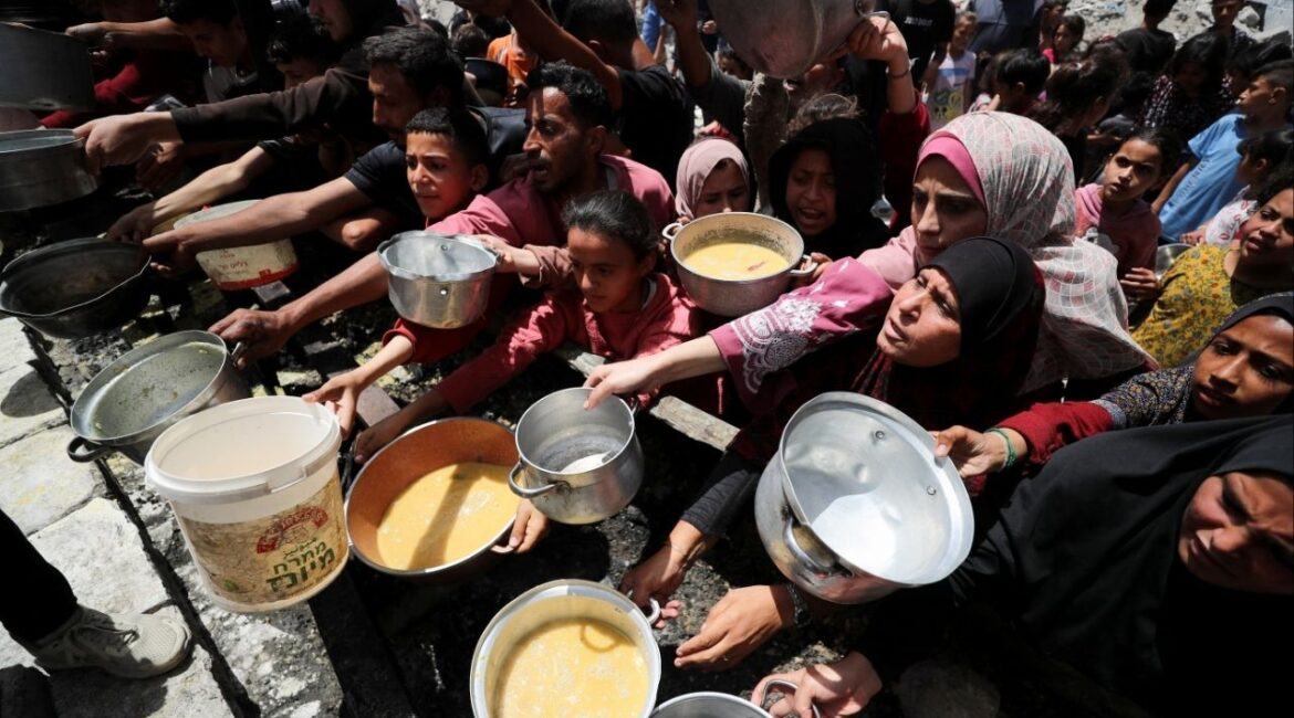 Palestinians wait to receive food cooked by a charity kitchen, in Jabalia, in the northern Gaza Strip, May 19, 2025. REUTERS/Mahmoud Issa