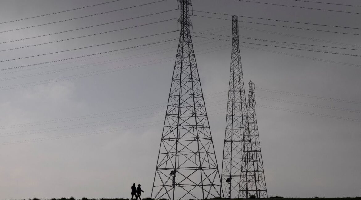 Residents walk by power grid towers at Bair Island State Marine Park in Redwood City, California, United States, January 26, 2022. REUTERS/Carlos Barria/File Photo