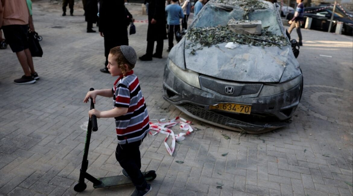 A boy rides a scooter near a damaged car at an impact site following Iran's strike on Israel, amid the Iran-Israel conflict, in Haifa, Israel, June 22, 2025. (Reuters/Florion Goga)