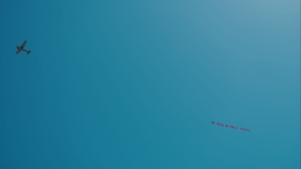 A plane flying over the event pulled a banner that read, “No Boys in Girls’ Sports!” as California’s state high school track and field meet in Clovis, near Fresno, Calif., on Friday, May 30, 2025. A transgender girl in California qualified for this week’s state high school track and field meet, and her inclusion in the two-day event has angered people who do not believe that trans girls should compete in girls’ events. (Adam Perez/The New York Times)
